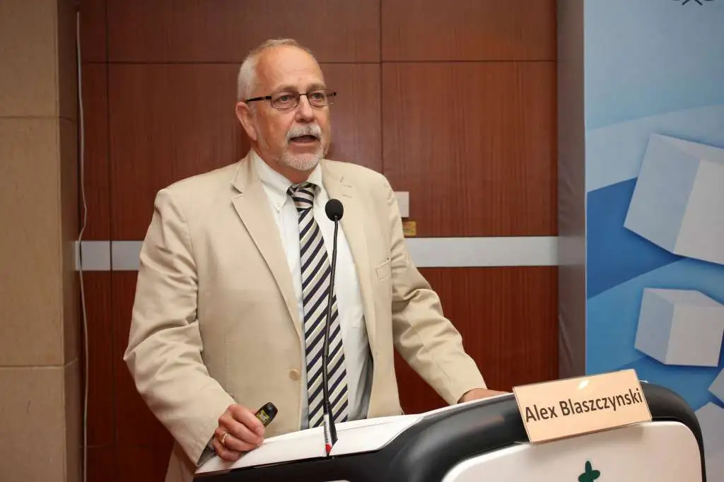 Autore in abito chiaro mentre parla a un podio durante una conferenza